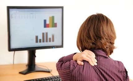 Trabajadora con dolor de hombro frente a la computadora